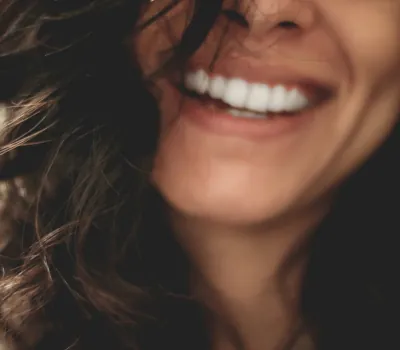 mulher branca desfocada sorrindo e mostrando os dentes brancos